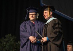 A graduate poses onstage with KCC President Dr. Dennis Bona during the College's 2014 commencement ceremony.