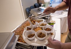 A photo of a patron at KCC's 2013 Chili Cook-Off filling a cup on his plate with chili.