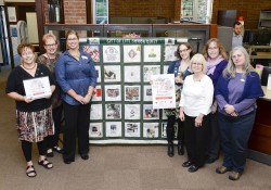 Library staff pose with an organ donor quilt in the library following an organ donation information event at KCC.