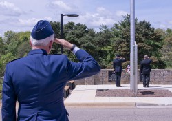 A KCC employee and veteran salutes during a Memorial Day ceremony outside on campus.