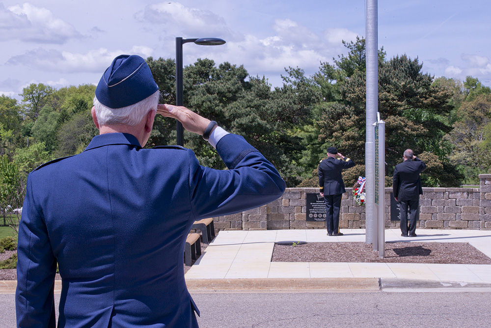 A KCC employee and veteran salutes during a Memorial Day ceremony outside on campus.