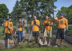 Student participants in Bruins Give Back pose while serving in KCC's community garden.
