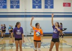 Two KCC volleyball players instruct a youth camper in the Miller Gym during a volleyball camp