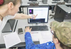 A computer programming instructor helps a student in class.