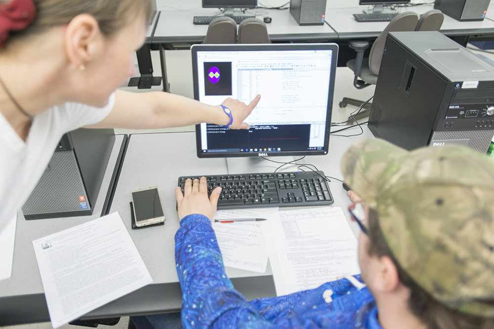 A computer programming instructor helps a student in class.