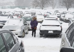 A student walks through a snowy KCC parking lot.