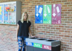 KCC alum Amber Hartlerode stands next to a new recycling station on KCC's North Avenue campus in Battle Creek.
