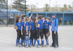 The KCC softball team meets on the field during a home game.