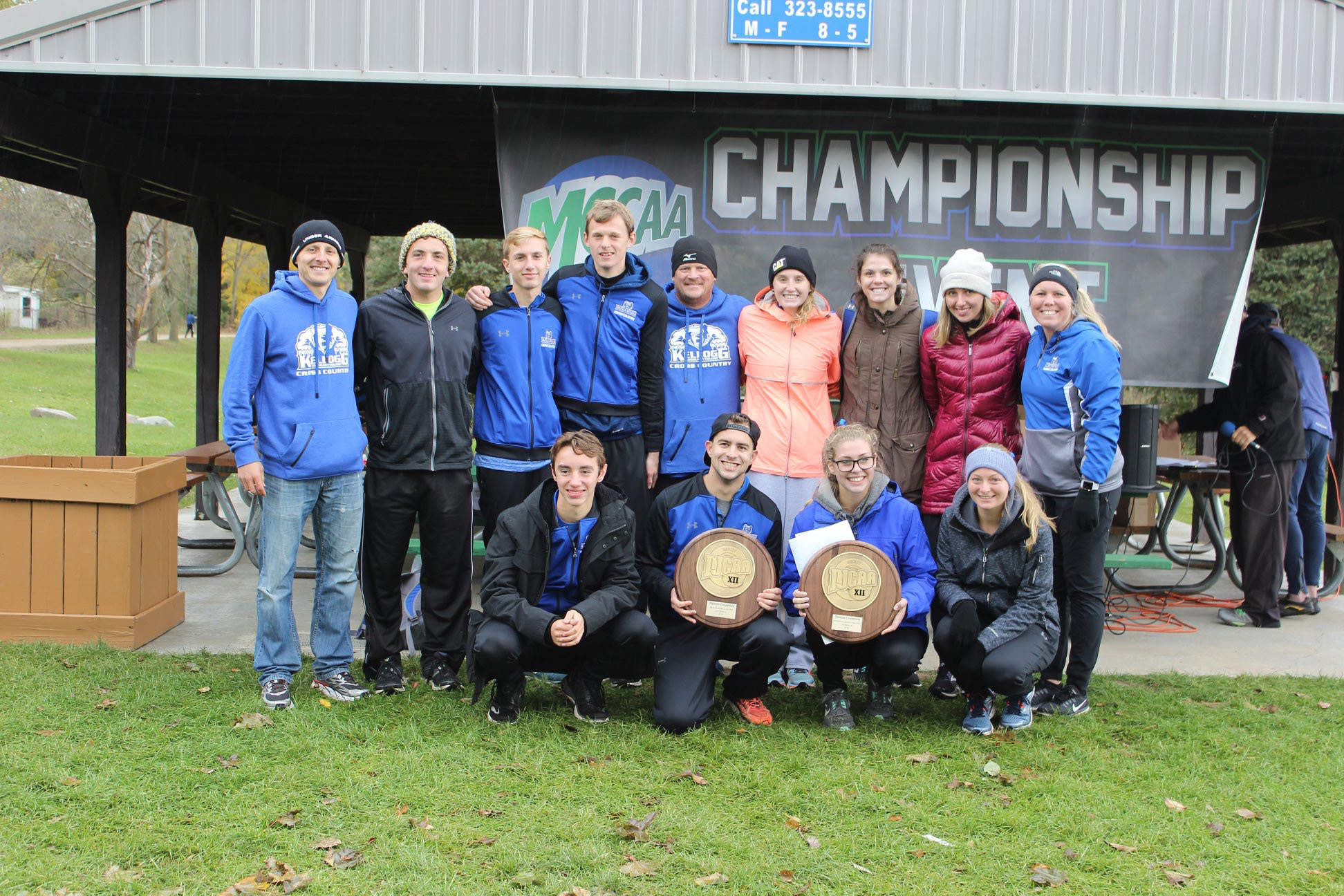KCC's men's and women's cross-country teams pose with trophies won for winning their respective regional championships.