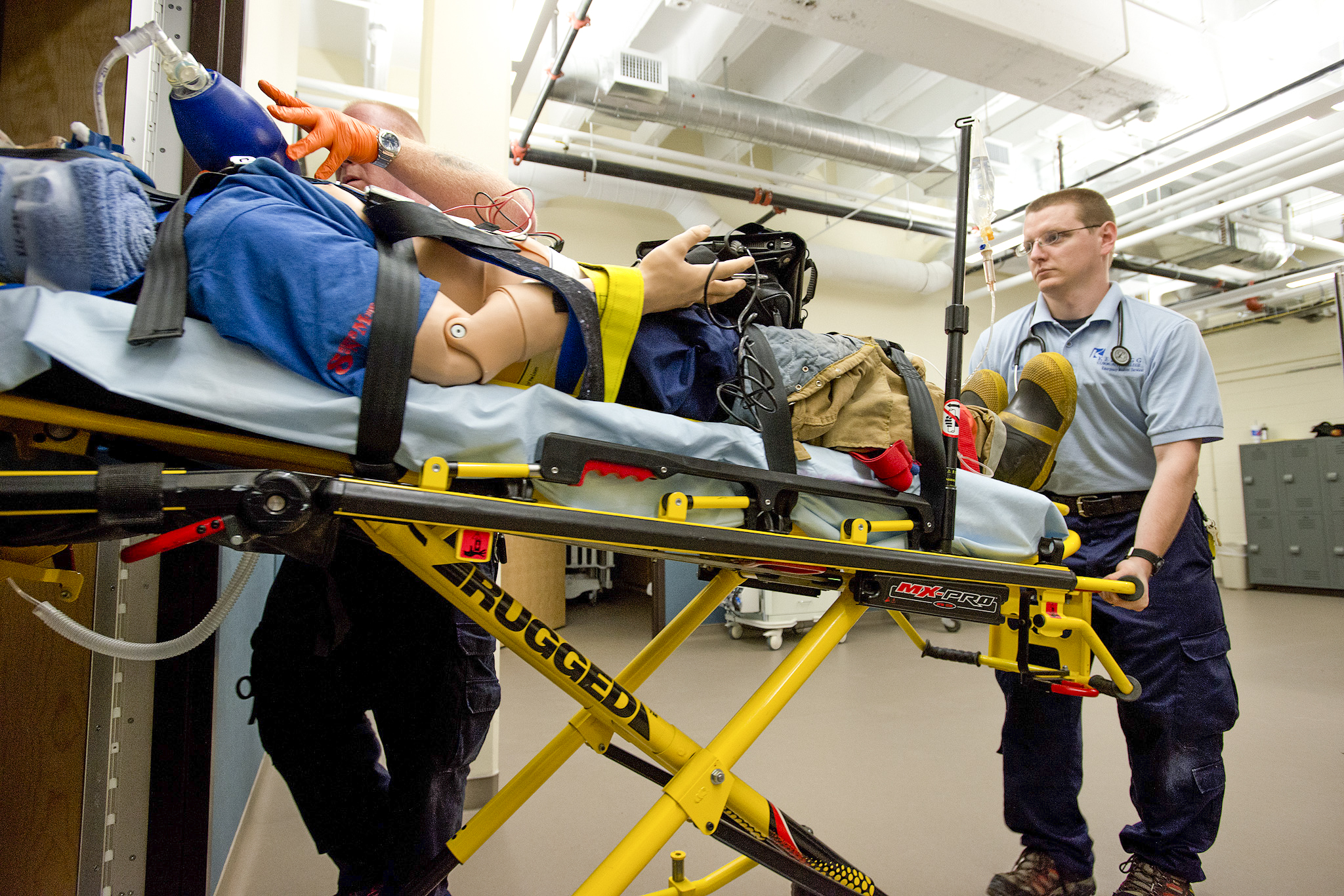 EMS students push a simulated patient on a gurney in the College's EMS sim lab.