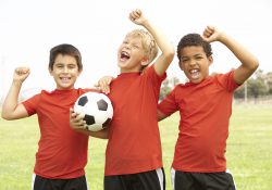 Three boys pose with a soccer ball.