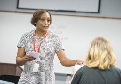 KCC alum and adjunct instructor Nikeesha Settles hands out papers during a class.