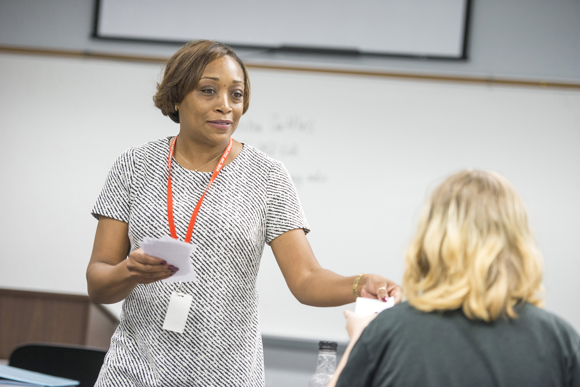 KCC alum and adjunct instructor Nikeesha Settles hands out papers during a class.