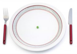 A fork and knife by a plate empty except for a single pea.