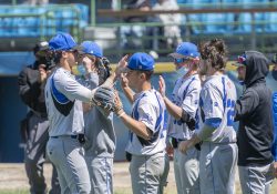 KCC baseball players high-five on the way to the dugout during a game.