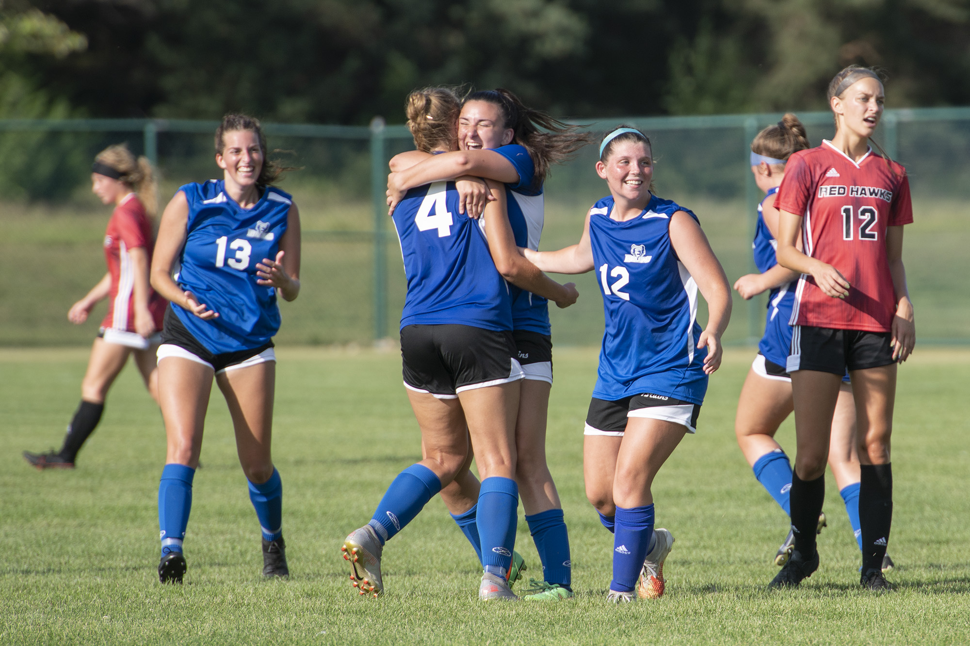 Members of the women's soccer team celebrate after scoring a goal.