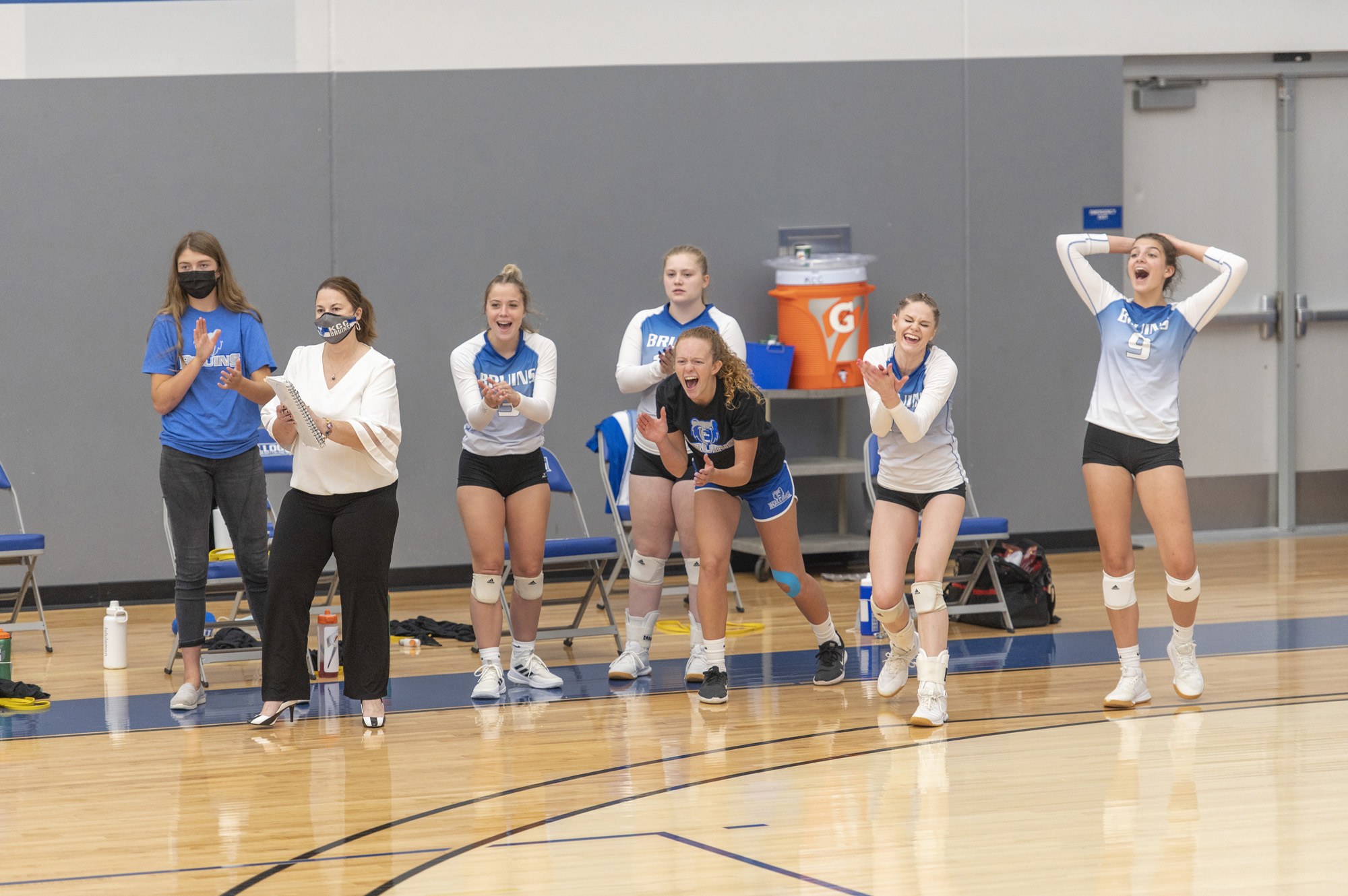 The women's volleyball team celebrates on the sideline after scoring a point.