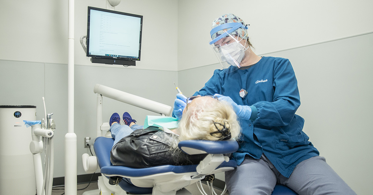 A Dental Hygiene student cleans a patient's teeth.