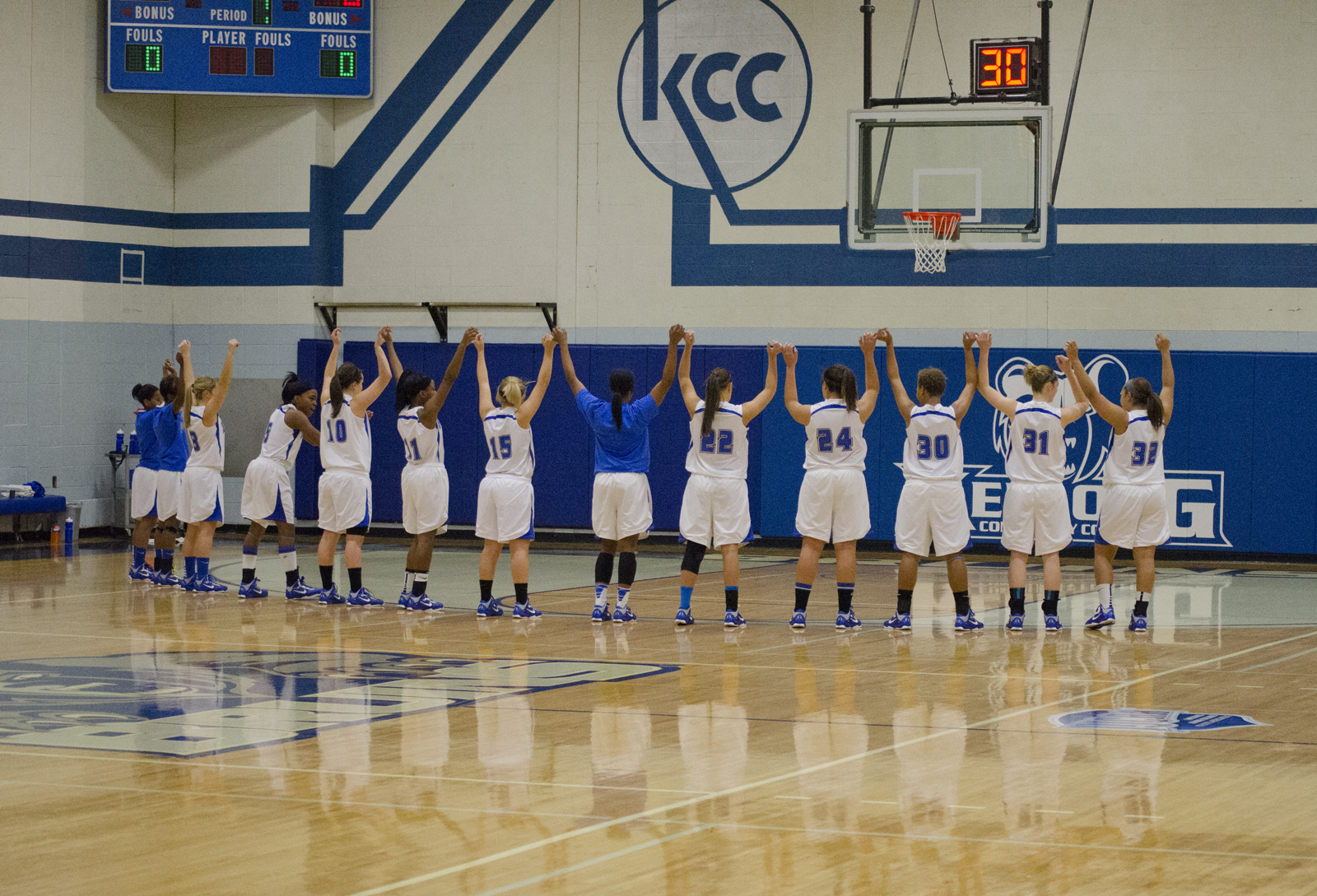 The women's basketball team holds hands over their heads in the Miller Gym before a home game.