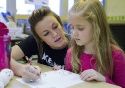 Mackenzie Kendall, 19, a centerfielder studying early childhood special education at KCC, helps a second grader with a worksheet.