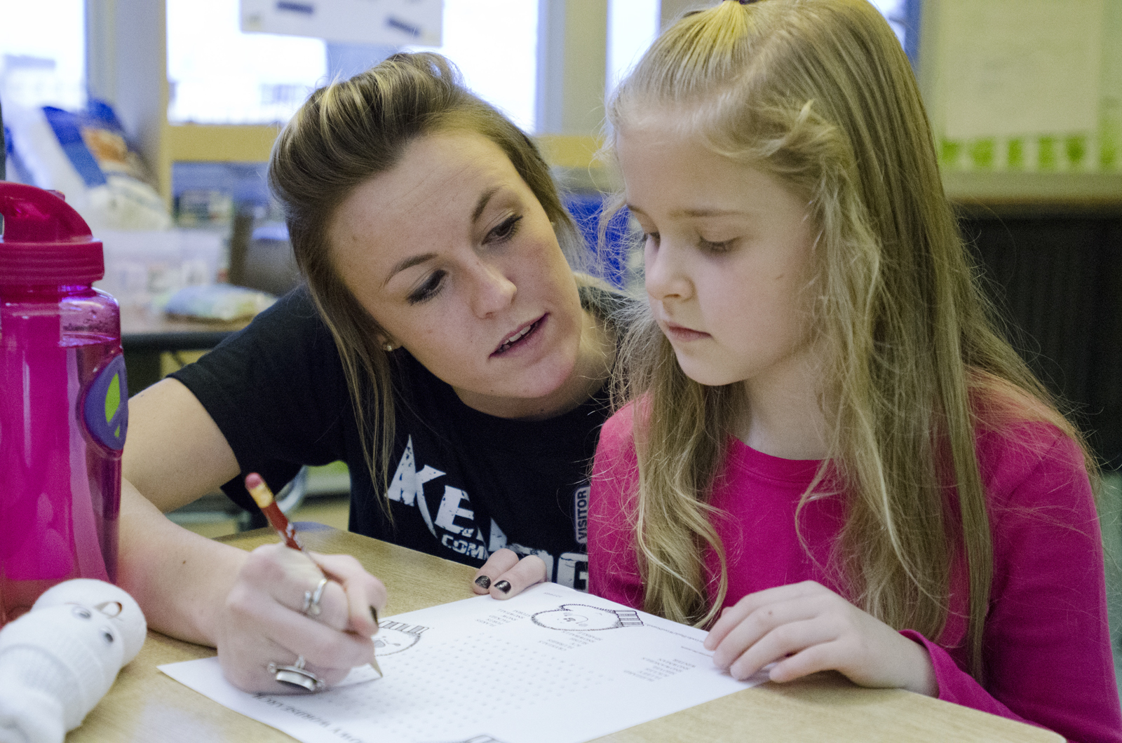 Mackenzie Kendall, 19, a centerfielder studying early childhood special education at KCC, helps a second grader with a worksheet.