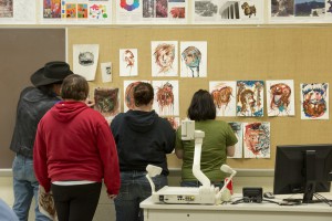 KCC art students hang paintings during a recent workshop.