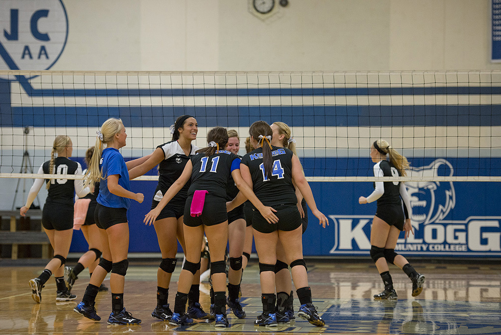 Women's volleyball players celebrate after scoring a point during a match at the Miller Gym.