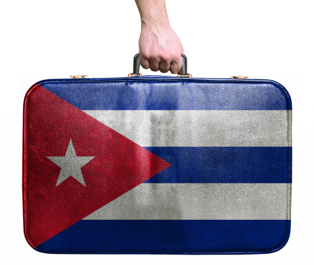 Tourist hand holding vintage travel bag with flag of Cuba