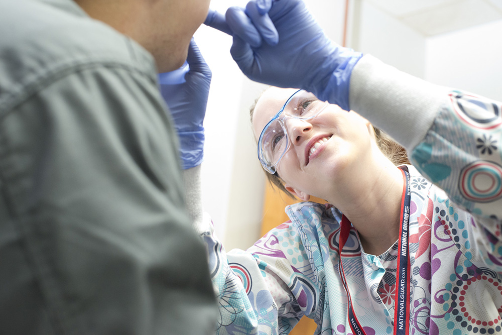 A dental hygiene student works on a patient