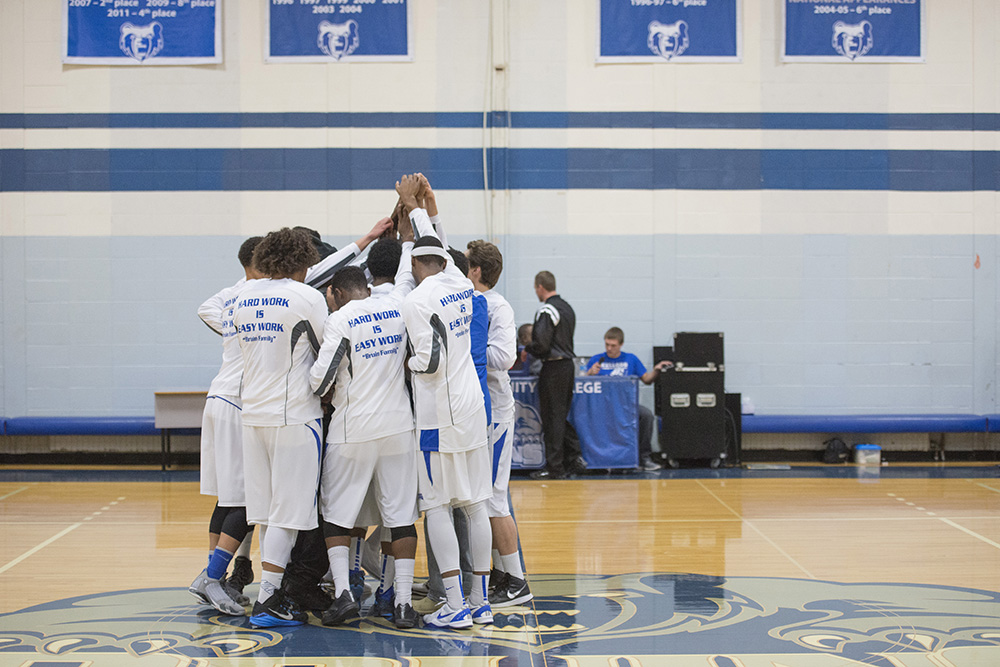 Members of the men's basketball team huddle on the court before a home game at the Miller Gym.