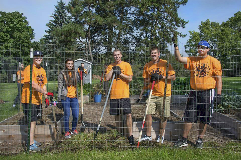 Student participants in Bruins Give Back pose while serving in KCC's community garden.