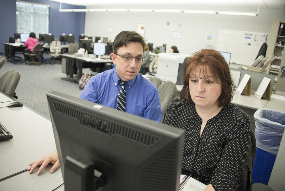 An instructor assists a student with work on a computer in a KCC computer lab.
