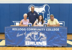 Miranda McDonald signs her National Letter of Intent to play women's volleyball for KCC, seated between her parents and in front of the team's coach.