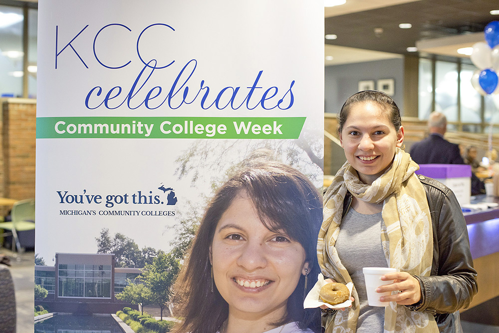 A student poses next to a community college poster featuring a photo of her