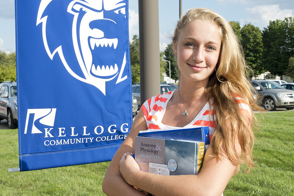 A student holding textbooks poses outside KCC's Grahl Center campus in Coldwater.