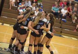 KCC's women's volleyball team huddles after scoring a point during a home match at the Miller Gym.