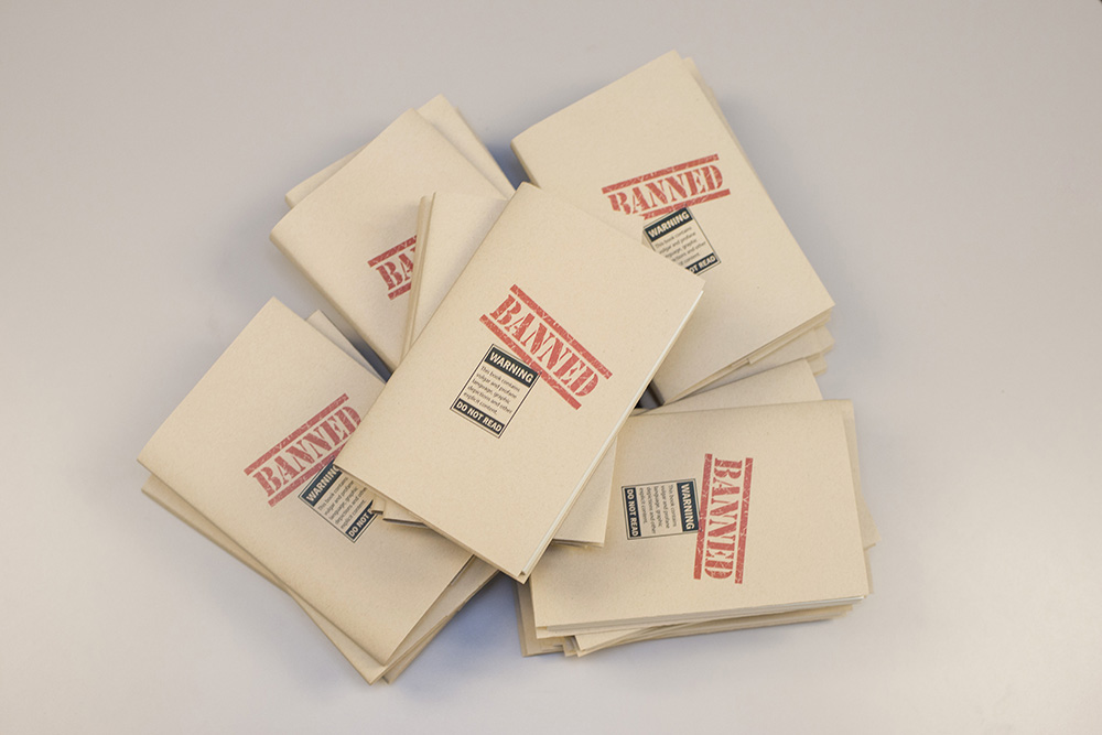 A stack of books wrapped in paper reading "banned."