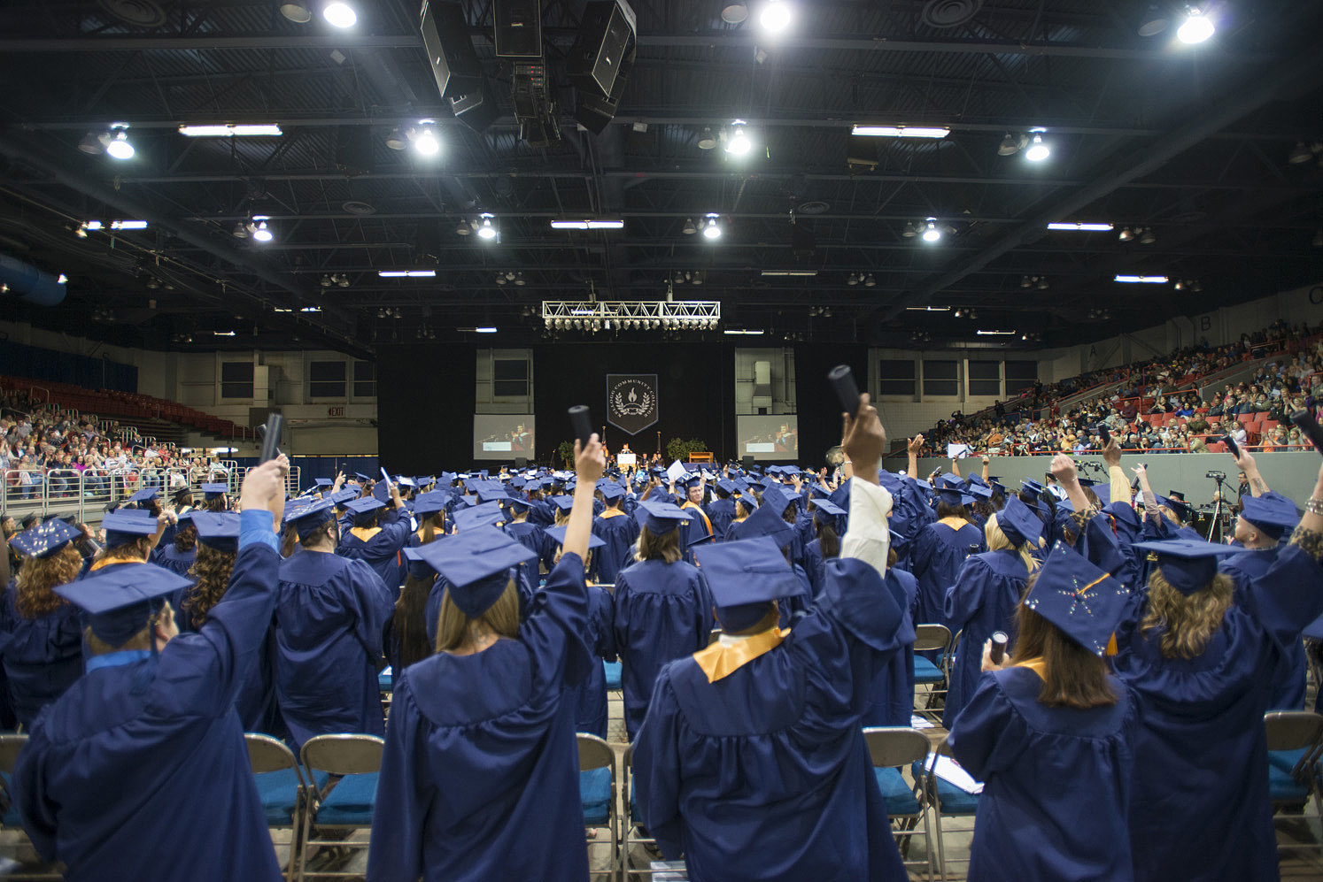 Graduates raise their hands in celebration following commencement.
