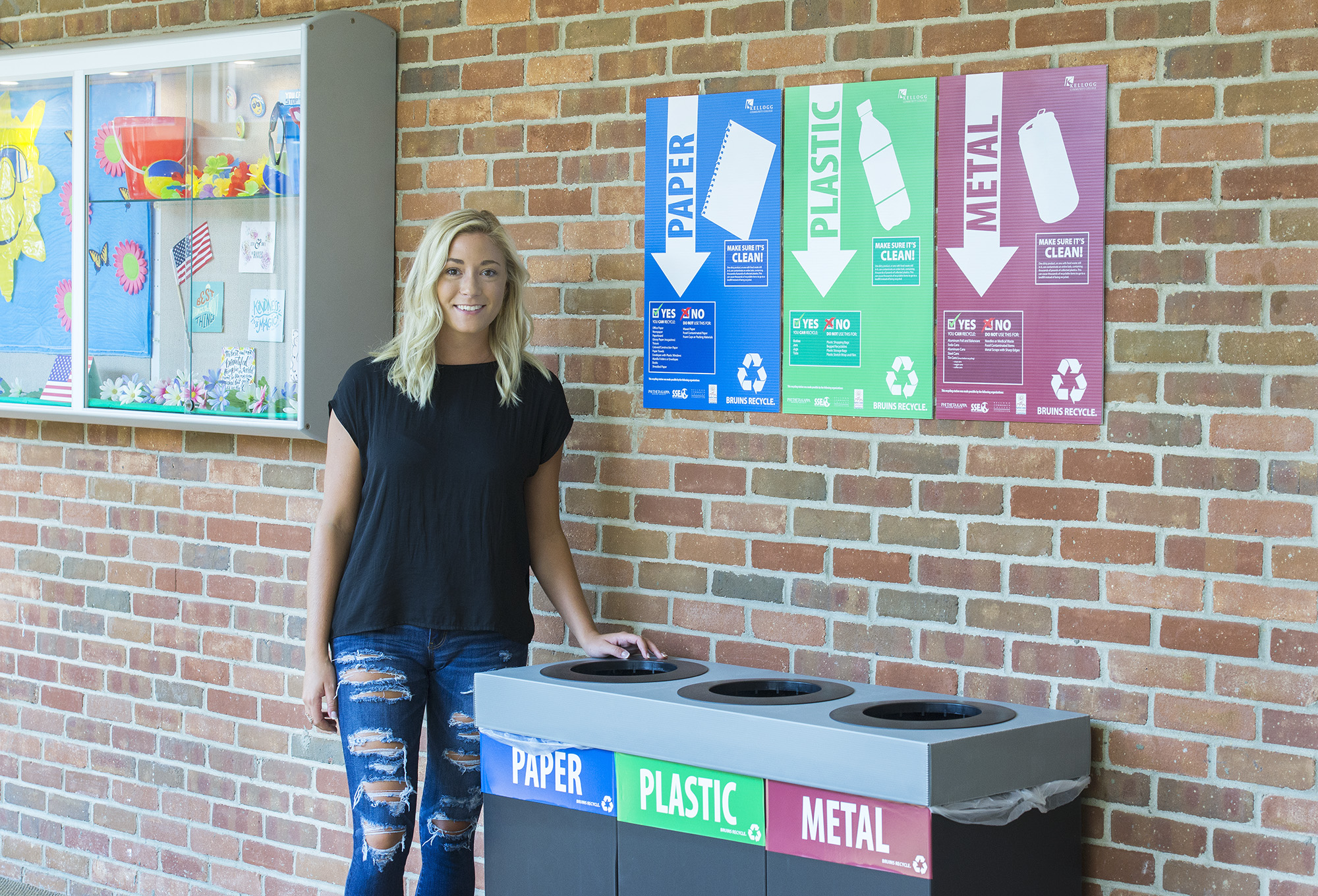 KCC alum Amber Hartlerode stands next to a new recycling station on KCC's North Avenue campus in Battle Creek.
