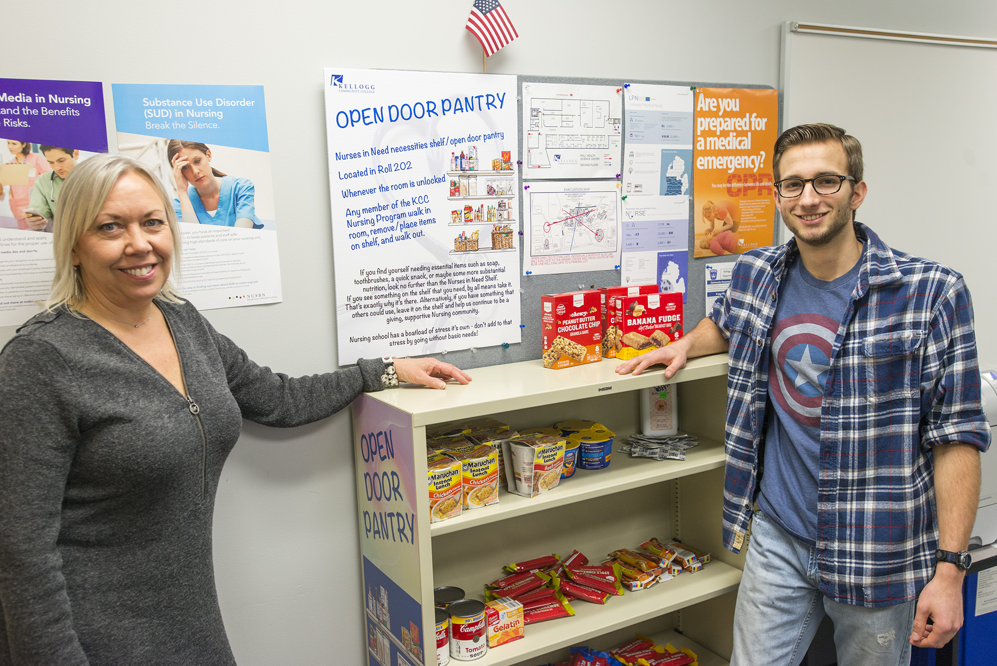 KCC Nursing professor Elizabeth Fluty, left, stands with Nursing student Isaac Lake by the Nurses in Need Open Door Pantry on campus in Battle Creek. The pantry is supplied by the KCC community to provide food, hygiene and other items to KCC Nursing students in need.