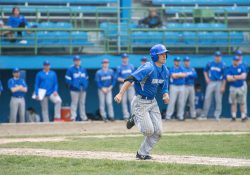 A KCC baseball player runs to first after hitting the ball during a home game.