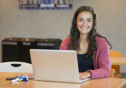 A student poses with a laptop in the Student Center.