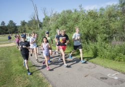 KCC cross country runners run with youth campers around Spring Lake.