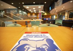 A sign encouraging visitors to campus to social distance at least 6 feet apart, affixed to a table in the Student Center.