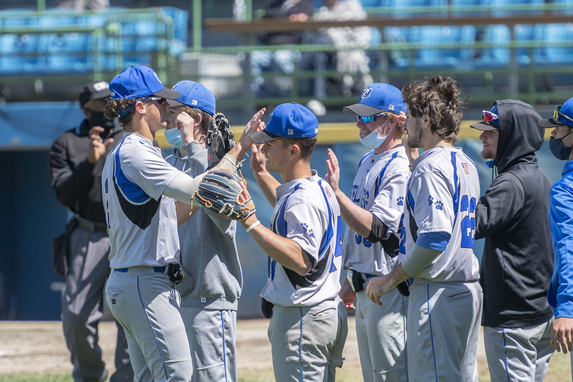 KCC baseball players high-five on the way to the dugout during a game.