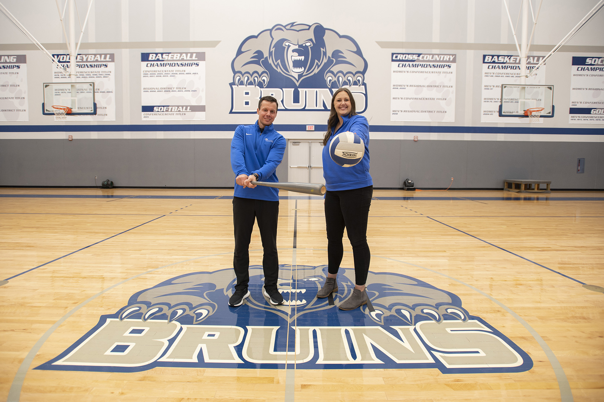 KCC Athletic Director Drew Fleming holds a bat and Assistant Athletic Director Mikayla Shell holds a volleyball in the Miller Gym.