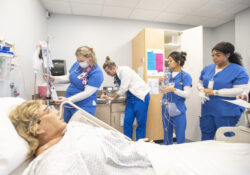 Four KCC Nursing students assist a patient during a simulation exercise.