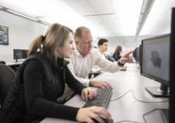 A CAD instructor assists a student with a computer project.