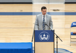 Drew Fleming speaks at a podium in the gym.