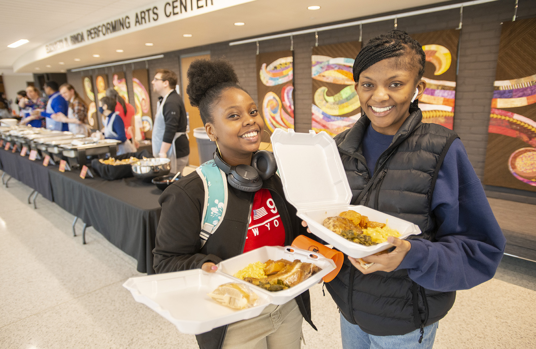 Students pose with takeout containers full of food during a Soul Food Luncheon event on campus.